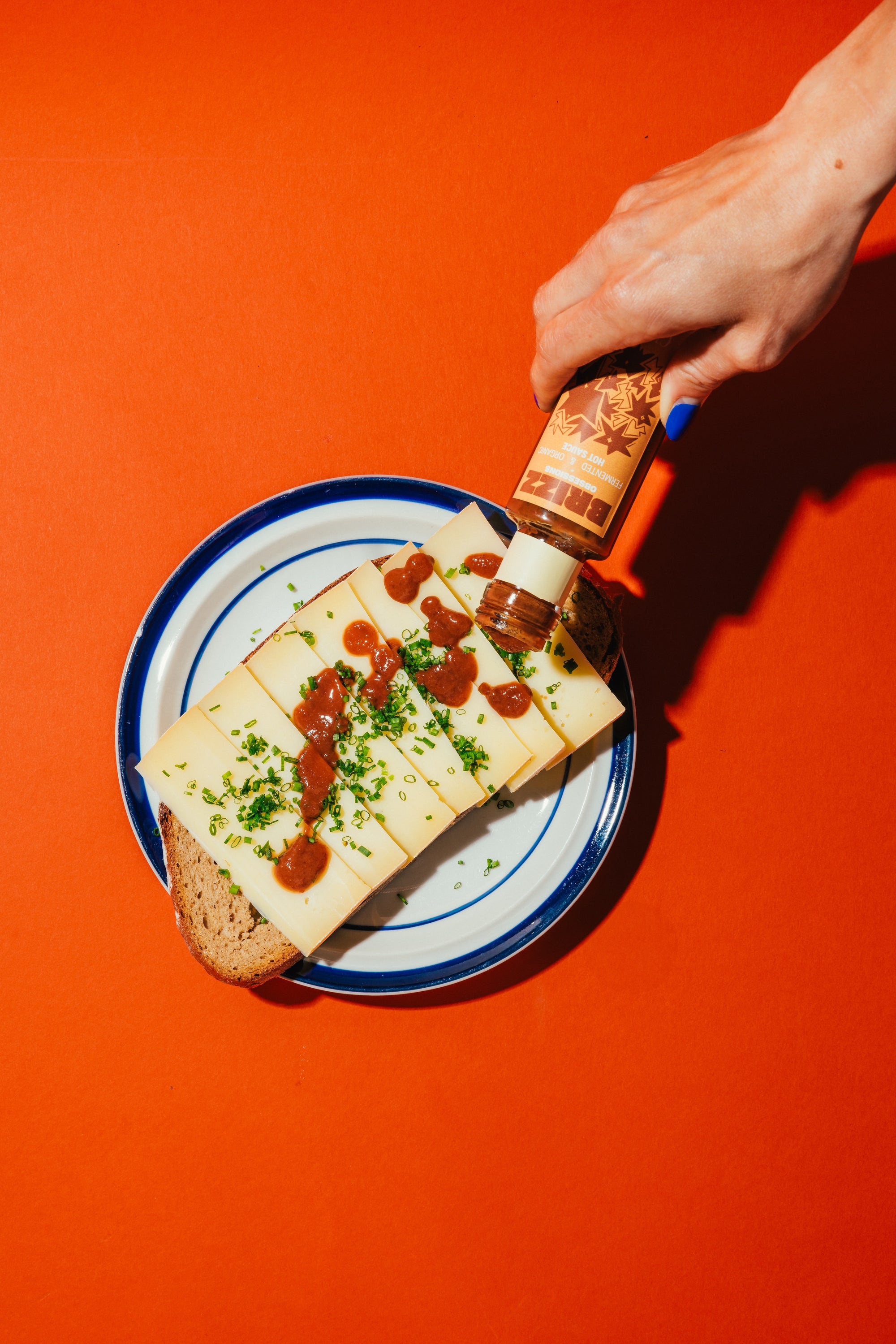BRIZZ Climax Hot Sauce wird über Käsebrot geträufelt – fruchtig-scharf mit Johannisbeere und Miso.