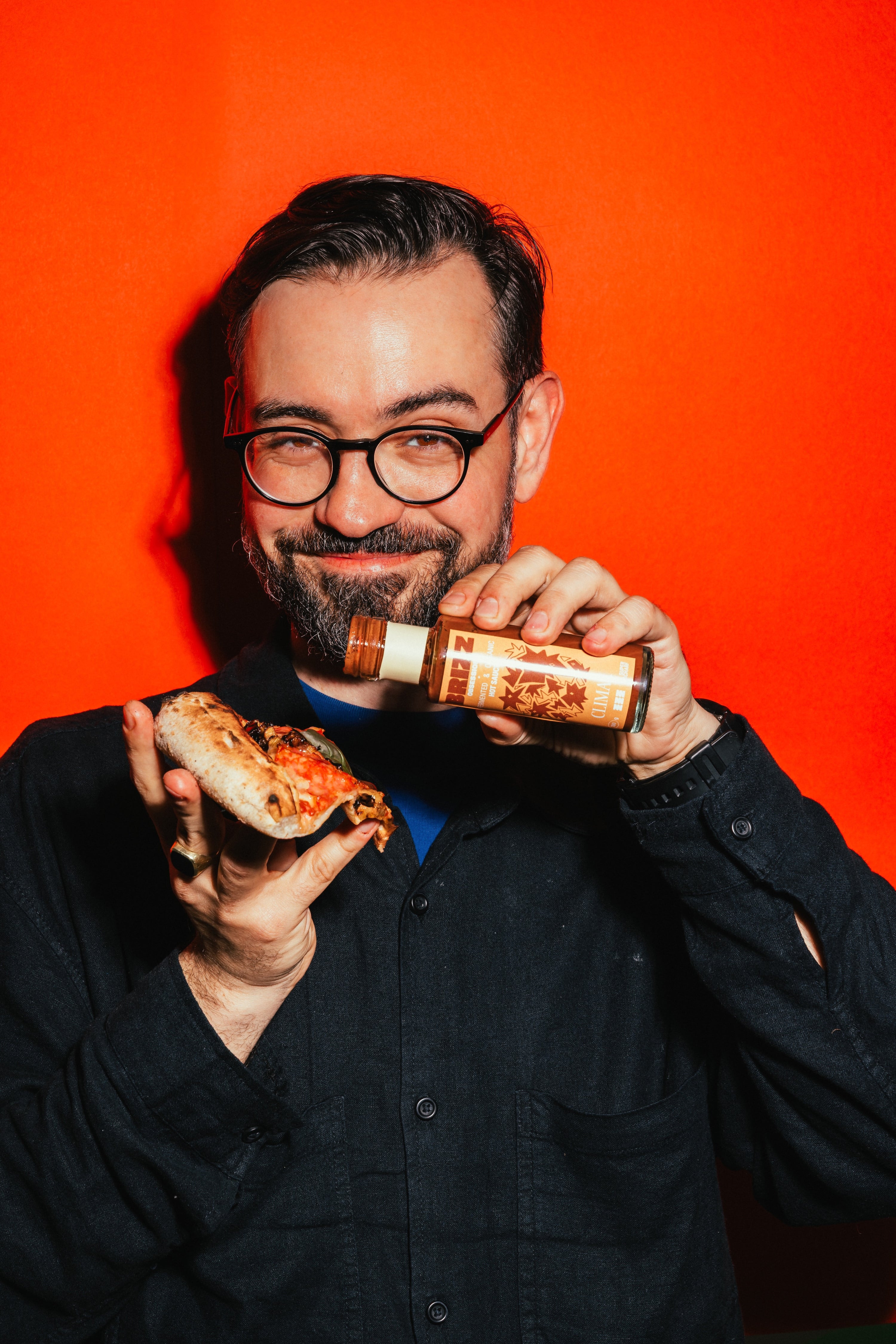 Ein Mann kostet BRIZZ Climax Hot Sauce auf einer Pizza – super scharfe fermentierte Bio-Sauce mit Johannisbeere.