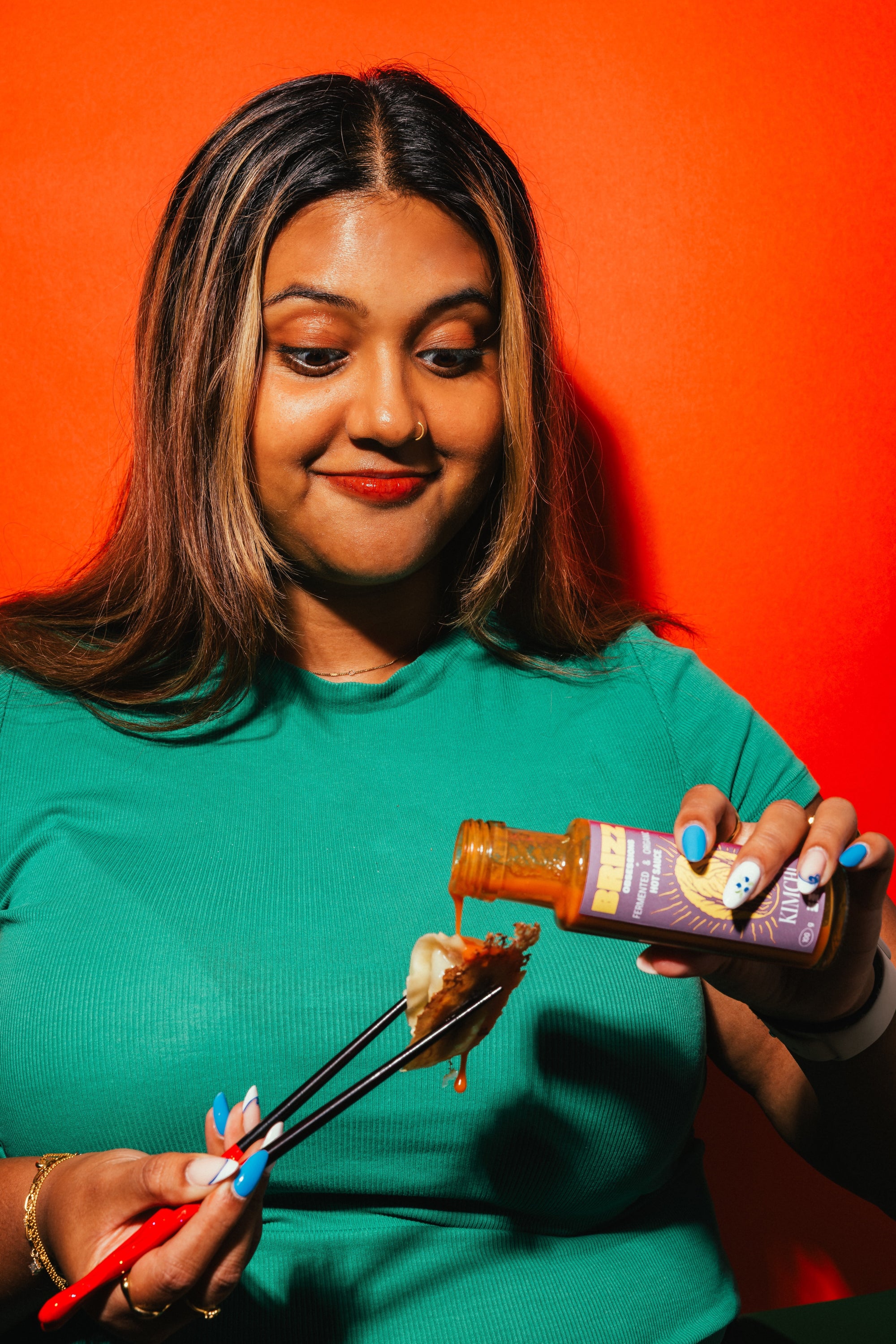 Frau genießt BRIZZ Kimchi Hot Sauce zu Dumplings, fermentiert und aromatisch.