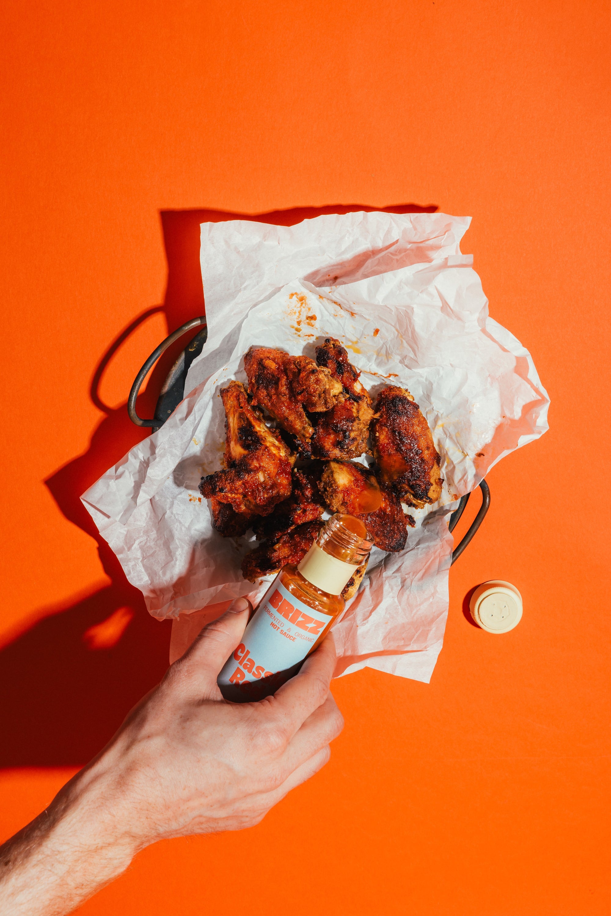 BRIZZ Classic Red Hot Sauce wird über Burger gegeben – Bio, fermentiert, scharf.