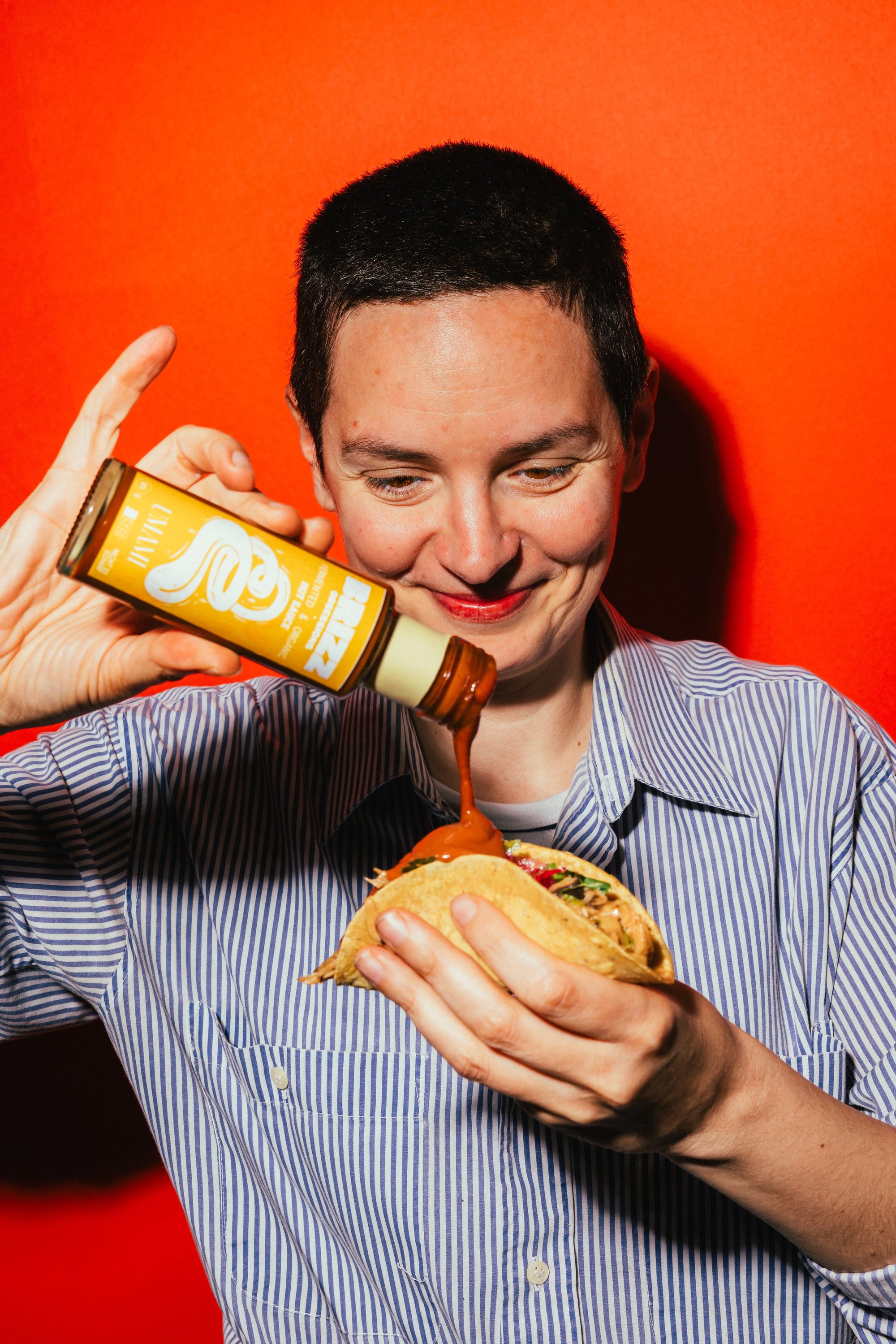 Person träufelt BRIZZ Umami Sauce über Taco – würzig, bio und aus Sojasaucen-Presskuchen upcycled.